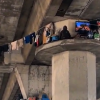 Unusual scene in Los Angeles: person appears to be living on top of a freeway overpass