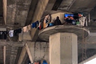 Unusual scene in Los Angeles: person appears to be living on top of a freeway overpass