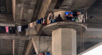 Unusual scene in Los Angeles: person appears to be living on top of a freeway overpass