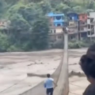 Man risks his life to cross flooded bridge and reach his family in Nepal