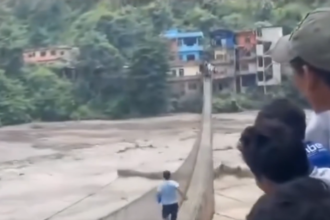 Man risks his life to cross flooded bridge and reach his family in Nepal
