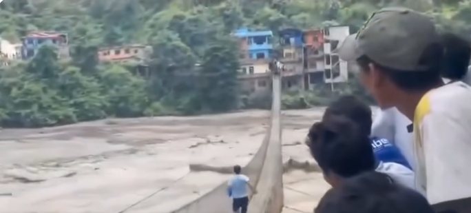 Man risks his life to cross flooded bridge and reach his family in Nepal