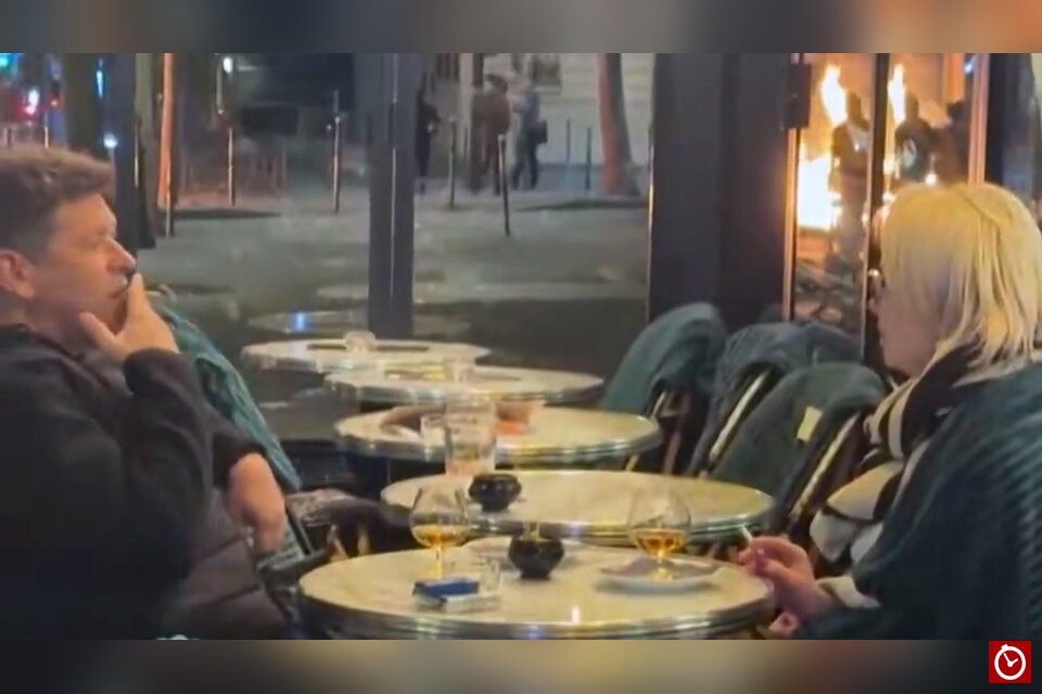 Couple sips cognac as protests rage in the background in Paris