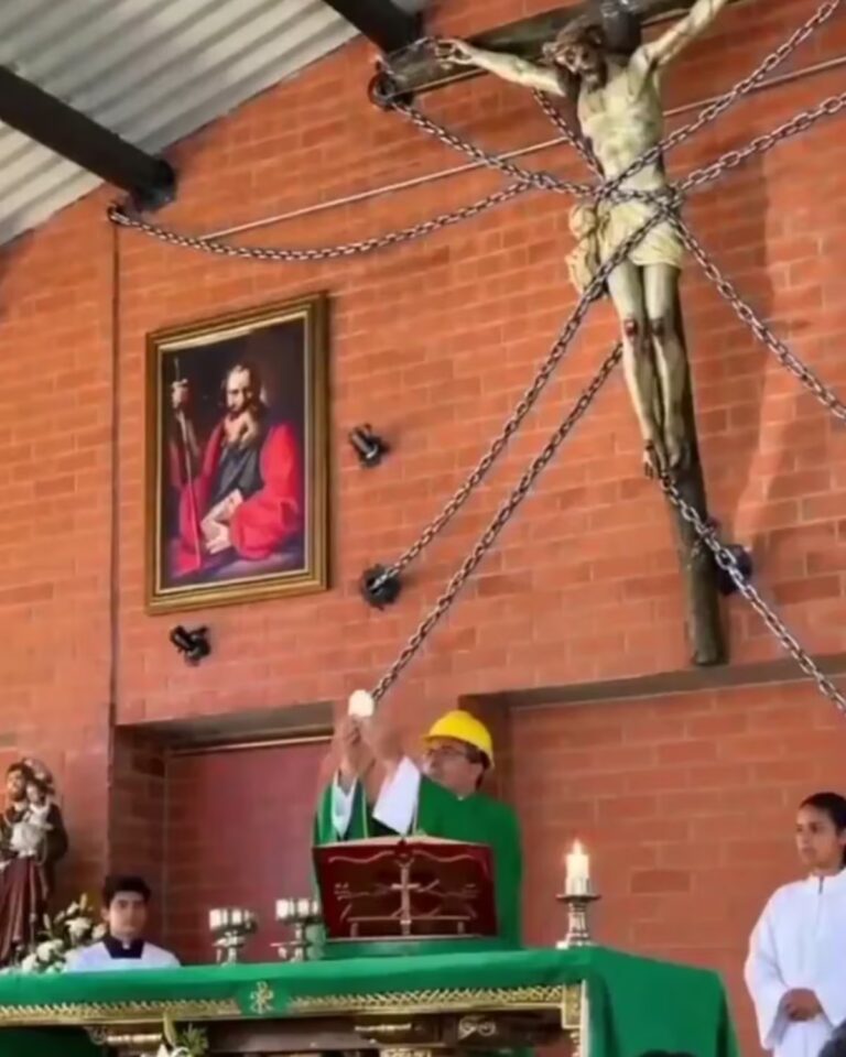 Priest wears construction helmet during Mass as chains secure statue of Christ