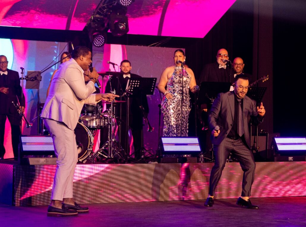 SANTO DOMINGO.- El Salón La Fiesta del emblemático hotel Jaragua de Santo Domingo fue el epicentro de una velada musical cargada de romanticismo y energía tropical. El cantautor puertorriqueño Joseph Fonseca celebró sus 25 años de carrera como solista con un concierto que quedó grabado en la memoria de sus seguidores, en el marco de su gira “Que levante la mano, 25 años tour”, que llegó a la capital dominicana bajo la impecable producción artística de René Brea y la producción general de Cifre Entertainment. Desde que el reloj marcó las 10:24 de la noche del Día del Amor, Fonseca encendió a un público que respondió con entusiasmo al ritmo de “Maniac”, en una escenografía de alta tecnología con pantallas gigantes y una nitidez musical desbordante. Acompañado por una envidiable orquesta conformada por 14 músicos boricuas y dominicanos, y una corista de lujo, el artista recorrió lo más trascendental de su exitoso repertorio que hizo vibrar un teatro La Fiesta completamente lleno: “Dame una oportunidad”, “Buscando tus besos” y “El queso” fueron solo algunos de los primeros temas coreados a todo pulmón. La conexión con los asistentes fue uno de los puntos álgidos de la noche, por lo que Fonseca agradeció repetidamente el apoyo de los dominicanos, recordando la influencia del merengue y la bachata en su carrera. “Estar en esta tierra, la tierra del merengue y la bachata, es un honor inmenso. Gracias por hacerme parte de su historia”, expresó visiblemente emocionado en el concierto que contó con el respaldo de Banreservas, Frontier, Viva, Grupo Telemicro, Victoria GXT, Hits 92, Radio República, Top Latina, KQ 94.5 y Super Q. Fonseca también tuvo su momento de balada con canciones románticas de diversos artistas: “No sé tú” (Luis Miguel), “Me va a extrañar” (Ricardo Montaner) y “Lo pasado pasado” (José José). Y no faltaron los clásicos salseros para invitar al público a bailar en el escenario mientras interpretaba temas como “Viejo motel”, “Que locura enamorarme”, “Devórame” y “Tú con él”, en compañía de una pareja de bailarines. Las sorpresas no se hicieron esperar cuando la leyenda de la música dominicana, Niní Cáffaro, compartió el escenario en un emotivo homenaje al Jaragua con la nostálgica “Luna sobre el Jaragua”. La interpretación conjunta fue recibida con una ovación estruendosa que culminó en el clásico “Por amor”, cantado por el público y Cáffaro con profunda emoción. El desfile de invitados continuó con Gabriel Pagán, Jandy Ventura y Josie Esteban, quienes aportaron su sello a la velada con interpretaciones de “A tan solo una hora”, “El disco raya’o” y “El moreno”. Uno de los instantes más íntimos de la noche llegó con el medley de bachatas y un homenaje al inolvidable cantautor dominicano Víctor Víctor, encabezado por “Mesita de noche”. La intervención de un violinista en vivo elevó la atmósfera a un nivel de excelencia, dejando al público extasiado antes de estallar en aplausos. El bloque de rancheras fue otro de los puntos fuertes, aderezado por un grupo de mariachi, para que Fonseca interpretara “El rey”, “Se me olvidó otra vez”, “Volver” y “Te pareces tanto a mí”, antes de fusionar el género con merengue para un cierre espectacular. "Un aplauso para el Mariachi Internacional", exclamó el cantautor puertoriqueño que disfruta del cariño de los dominicanos. El final llegó con “Que levante la mano” y “Noche de fantasía”, provocando que el público se parara nuevamente a bailar en pistas improvisadas entre las mesas. Pero la noche no terminó ahí: un encore con “El africano” ‘cerraría’ el concierto, con cuatro parejas de baile en el escenario y una sala completamente entregada. Fonseca se despidió con un mensaje de gratitud: "Gracias, Santo Domingo. Esta noche queda en mi corazón". Pero los fanáticos corearon a todo pulmón “otra, otra”, y lo hicieron regresar al escenario a las 12:52 de la madrugada con “Noche de fantasía”. Sin duda, Joseph Fonseca protagonizó una velada para la historia, donde la música, la nostalgia y la pasión se fusionaron en un homenaje inolvidable a 25 años de carrera y a la hermandad entre Puerto Rico y la República Dominicana.