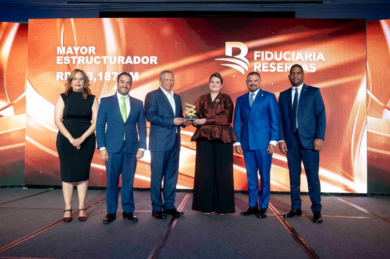 El doctor Leonardo Aguilera, presidente ejecutivo de Banreservas, recibe el premio que reconoce a la Fiduciaria Reservas como Mayor Estructurador en premios BVRD 2025. Desde la izquierda, Laura de Jansen, gerente de Operaciones de BVRD; Juan Mustafá, vicepresidente ejecutivo senior de Empresas Subsidiarias Banreservas; Elianne Vilchez, vicepresidente de Bolsa y Mercados de Valores de la República Dominicana; Andrés Vander Horst, vicepresidente ejecutivo de la Fiduciaria Reservas; y Juan Carlos Mañón, director financiero y de contabilidad.