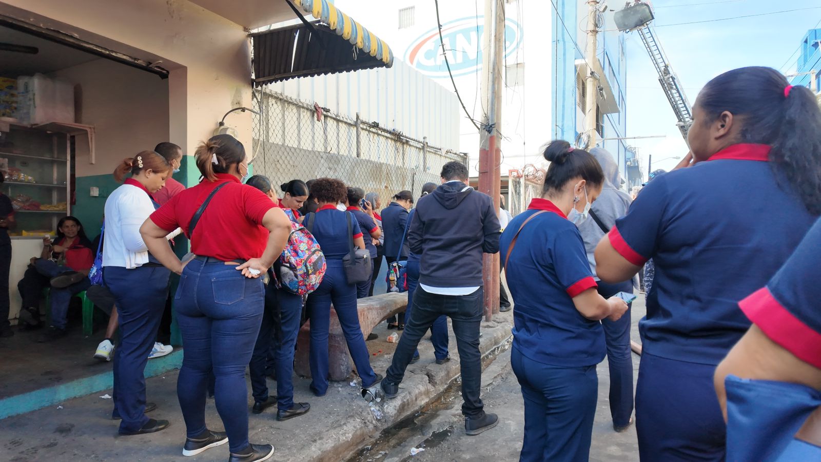 Empleados de Tiendas Garrido aguardan instrucciones mientras bomberos sofocan incendio en almacén