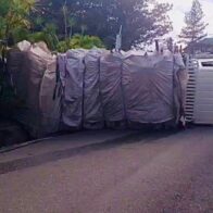 Camión cargado de desechos de madera se vuelva en cuesta hacia Jumunuco, Jarabacoa