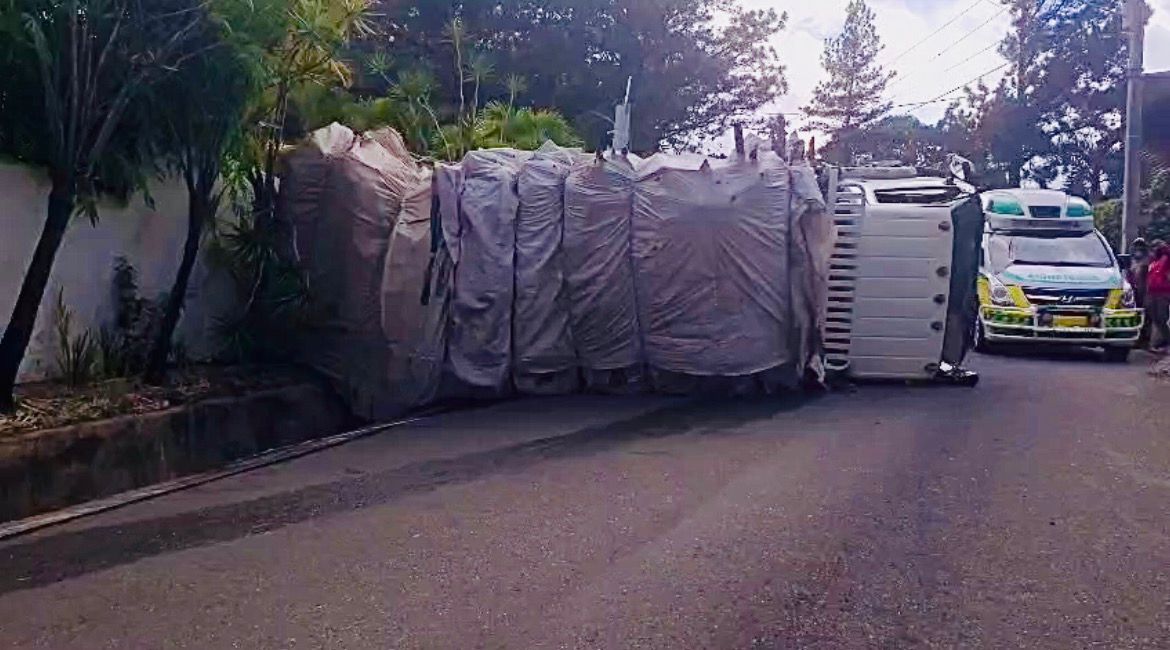 Camión cargado de desechos de madera se vuelva en cuesta hacia Jumunuco, Jarabacoa
